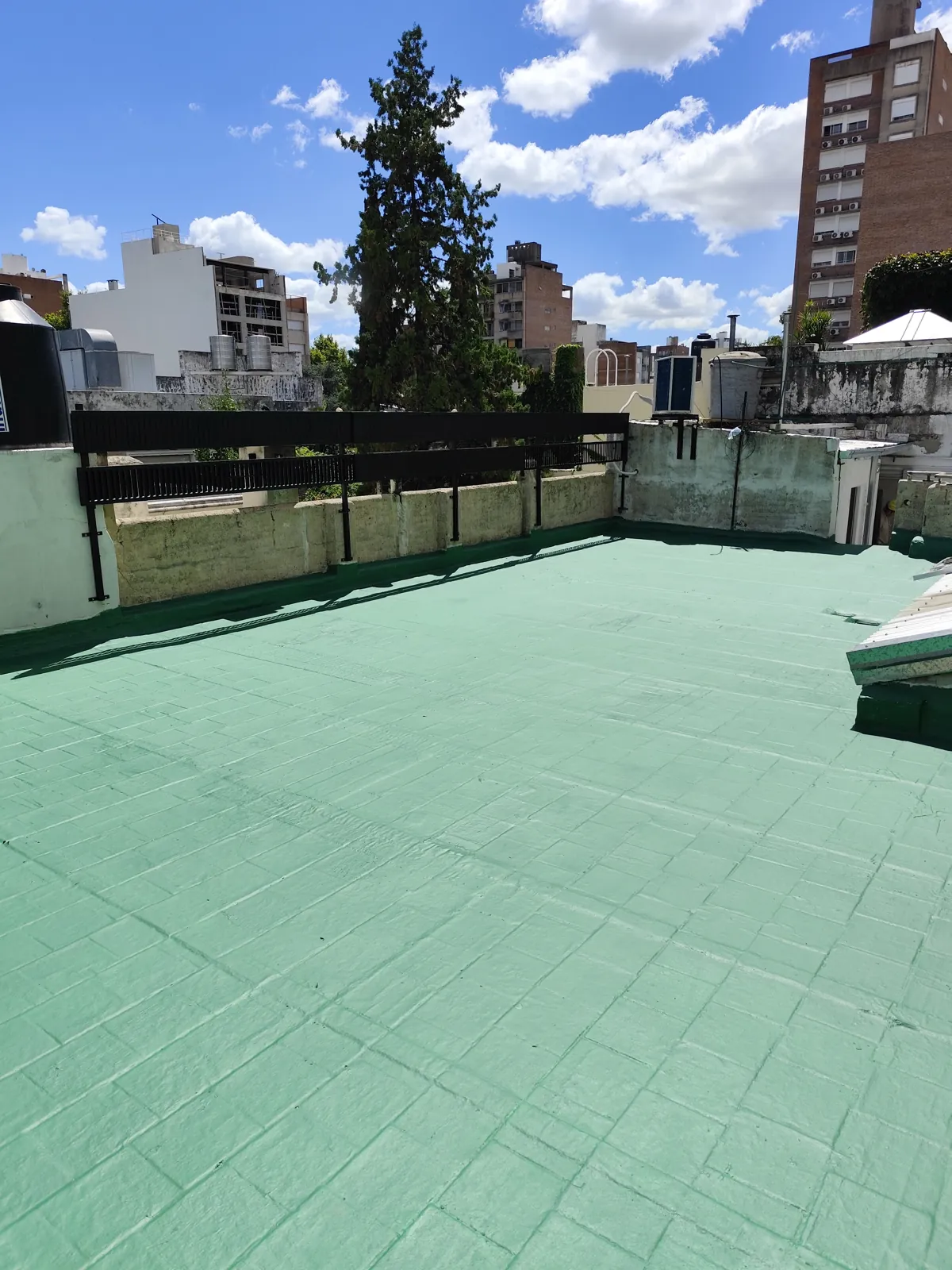 Terraza terminada con membrana verde, entre edificios.