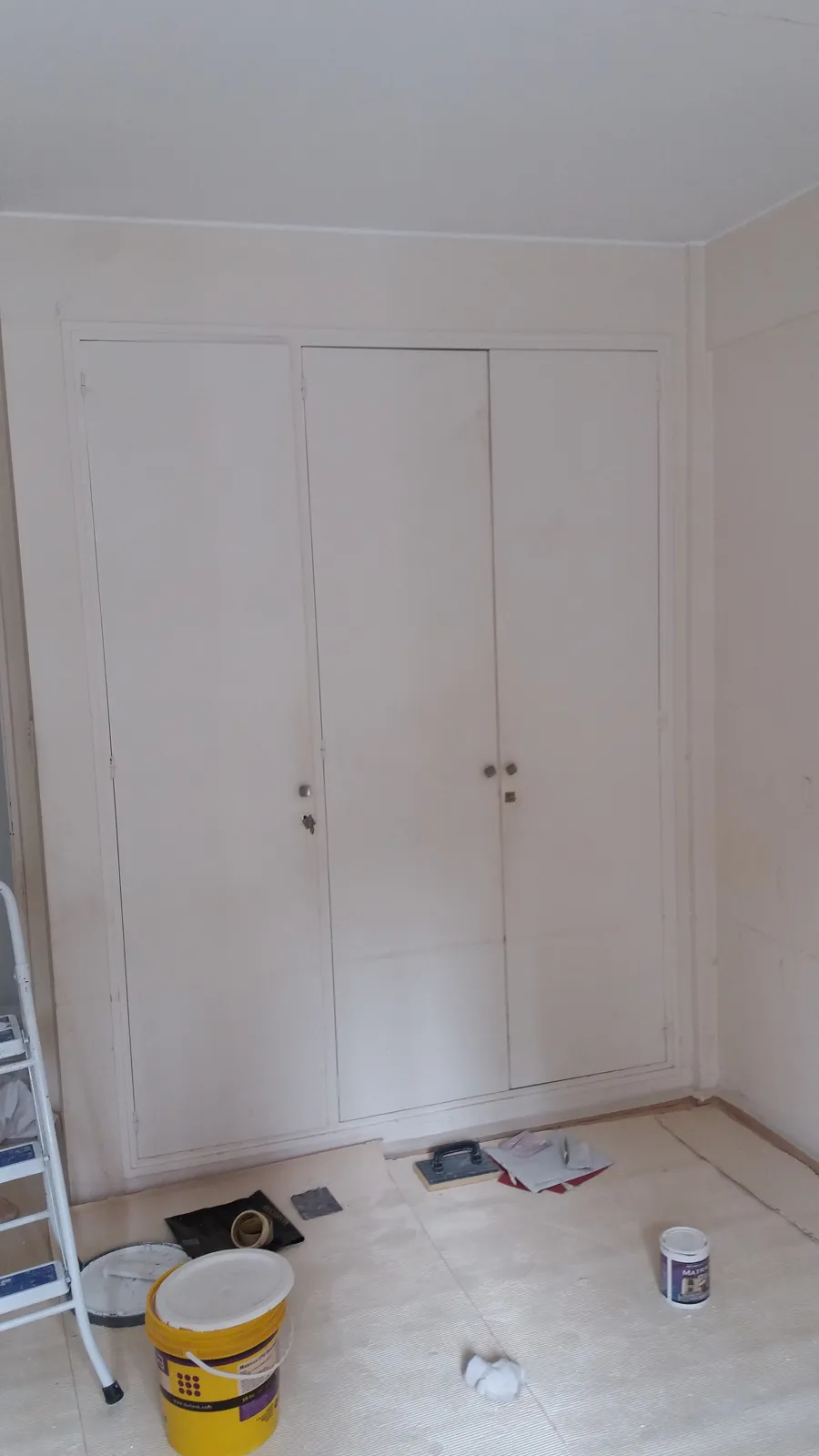 Placard blanco en pintura, con escalera y materiales en el piso.