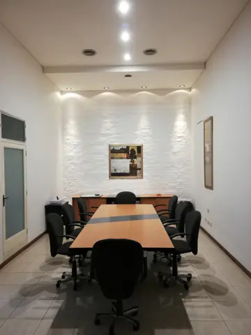 Sala de reuniones pintada de blanco con mesa larga.