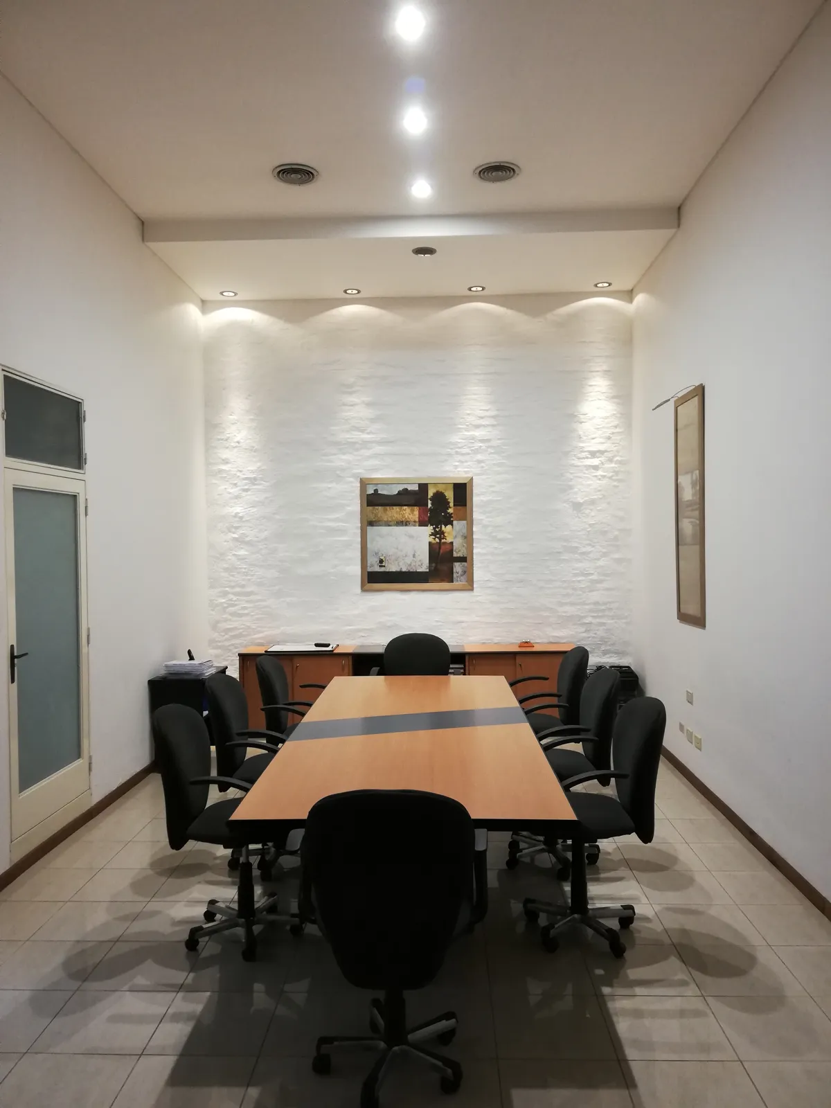 Sala de reuniones pintada de blanco con mesa larga.