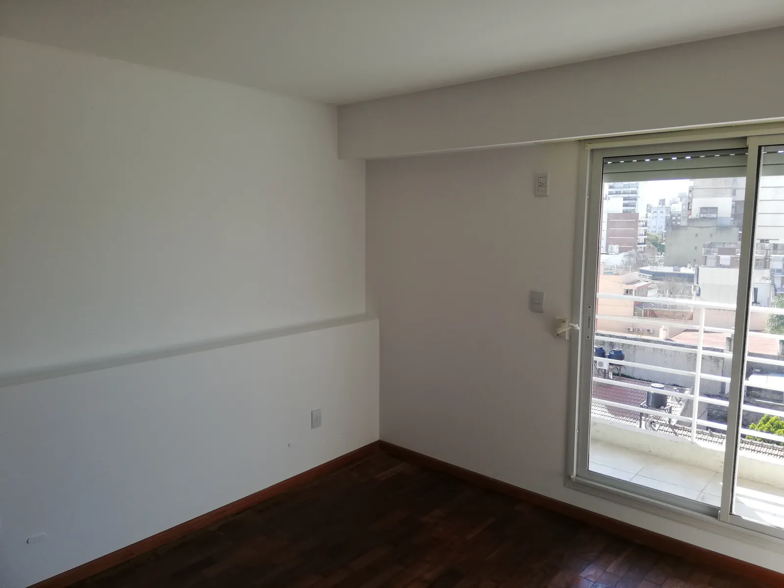 Departamento pintado de blanco con salida al balcón.