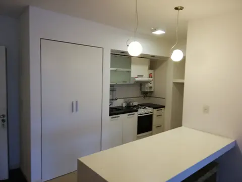 Cocina blanca con isla, paredes recién pintadas.