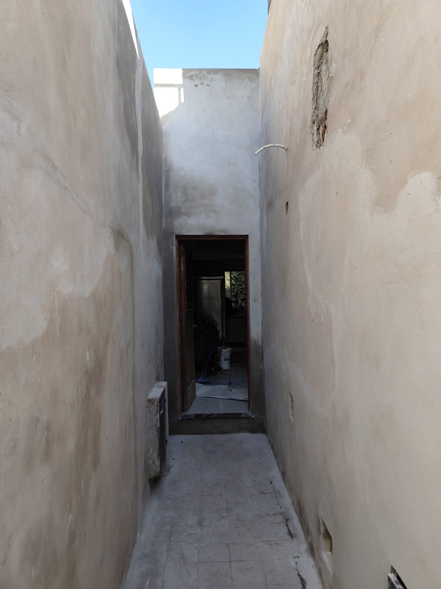 El mismo pasillo con las paredes revocadas y la puerta al fondo.