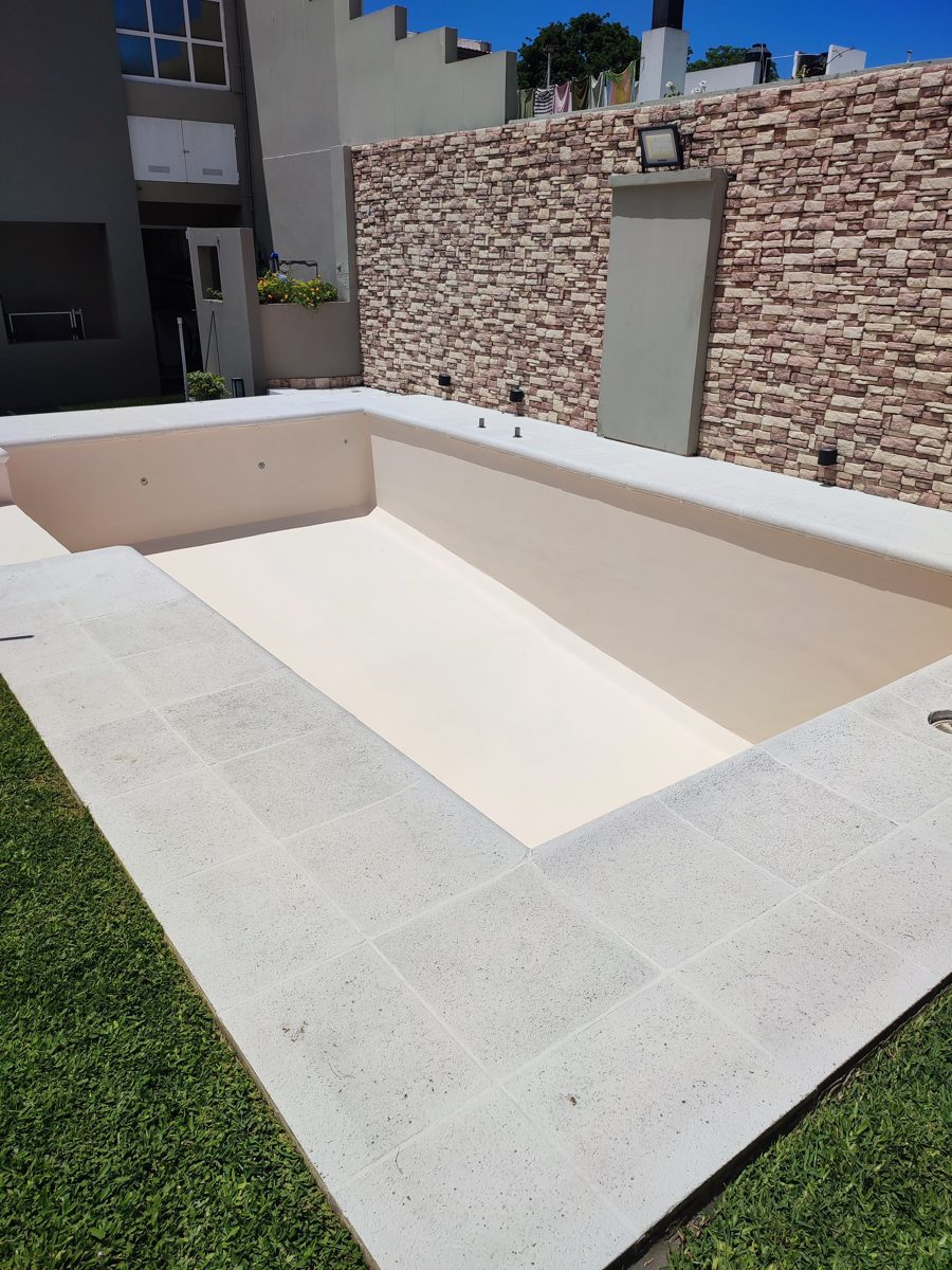 Pileta terminada pintada de blanco, con borde de baldosas claras.