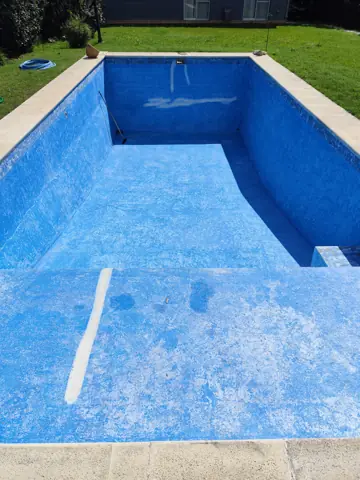 Pileta vacía con pintura azul gastada y descascarada.