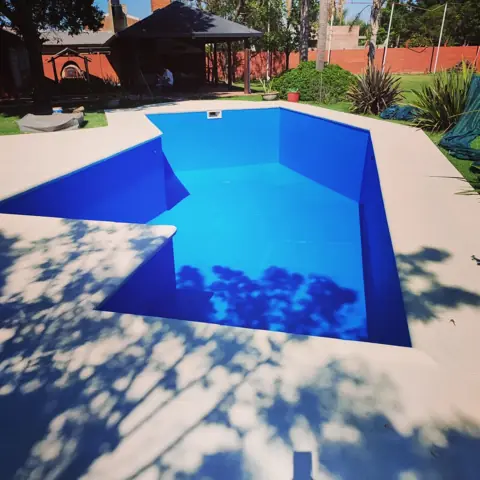 Pileta pintada de azul intenso en un jardín.