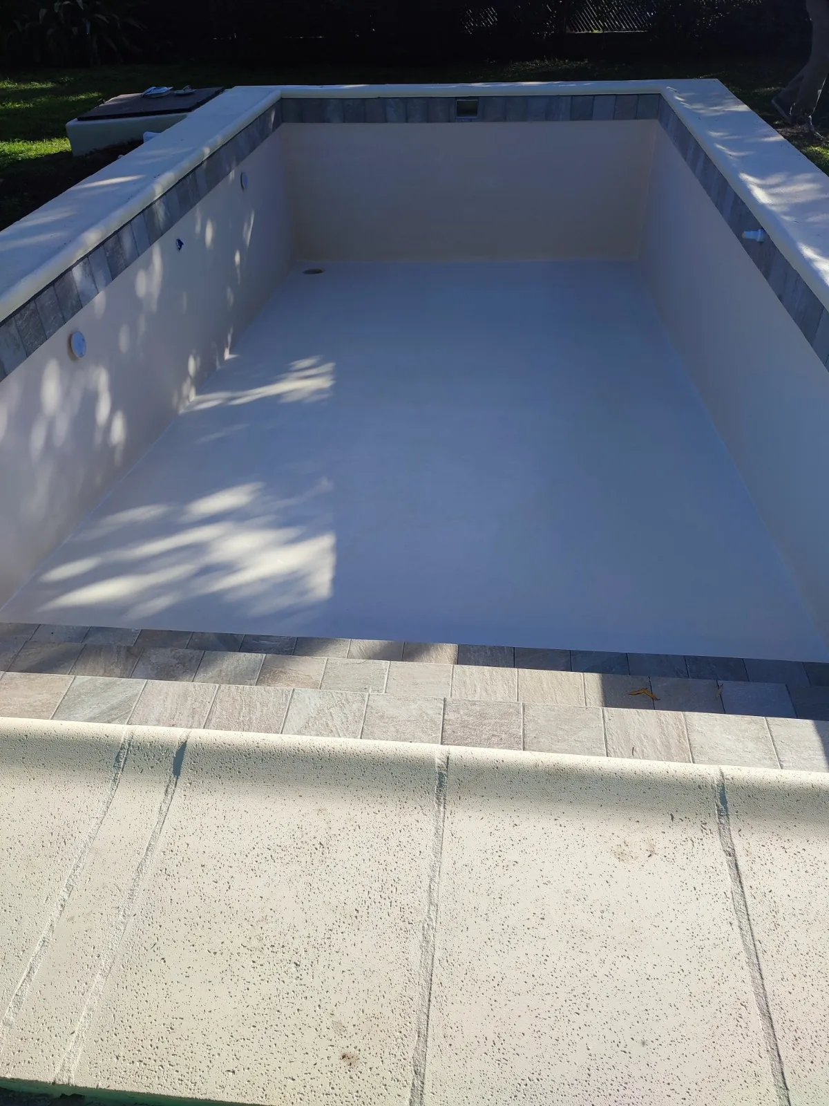 Pileta vacía con línea de venecitas en el borde.