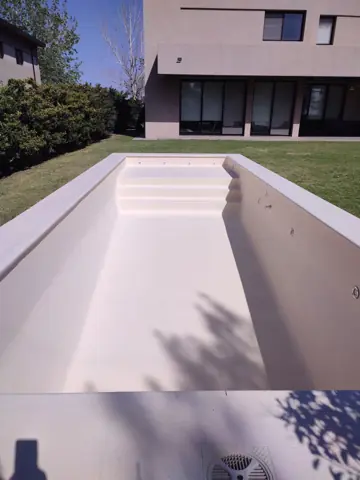 Pileta vacía pintada de color claro, con escalones.