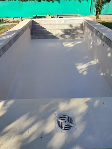 Pileta vacía en color claro, con rejilla de fondo.